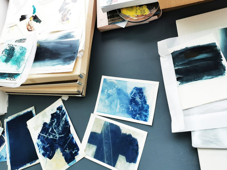 Artistic inkjet prints on paper with blue and black abstract designs on a dark surface.