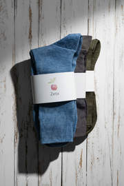 Three pairs of socks, one blue, one purple and one brown, with a Zeta label on a wooden surface.