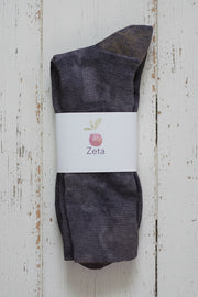 Dark mottled purple sock with a white label on a wooden surface