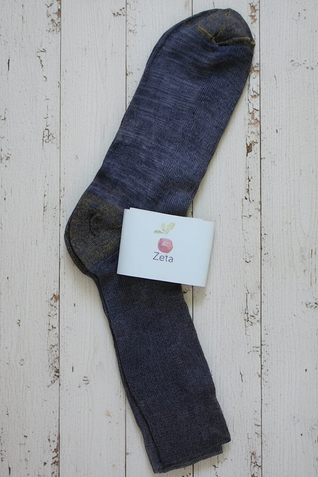Dark purple unfolded sock with a white label on a wooden surface
