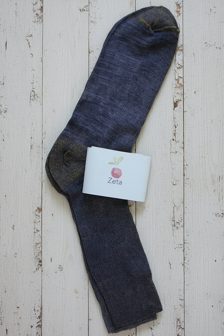 Dark purple unfolded sock with a white label on a wooden surface