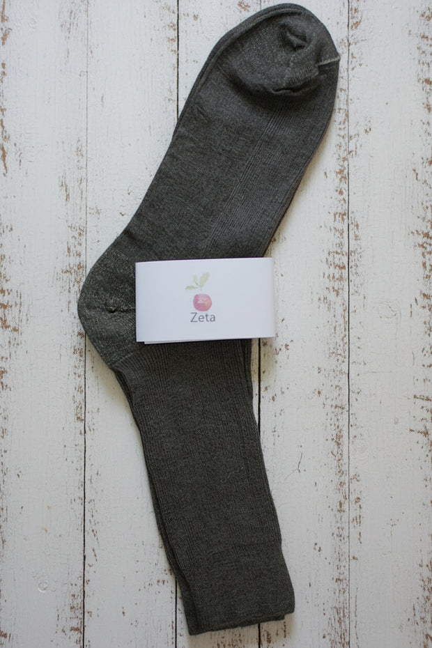 Brown unfolded sock with a white label on a wooden surface