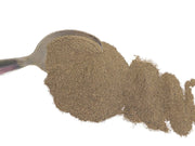 Spoonful of brown dyers broom extract  powder on a white background