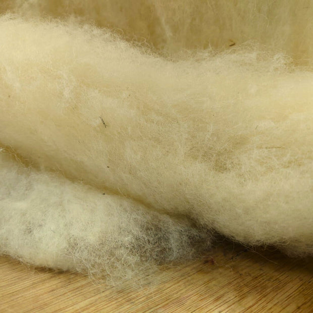 Close-up of raw wool fibers on a wooden surface