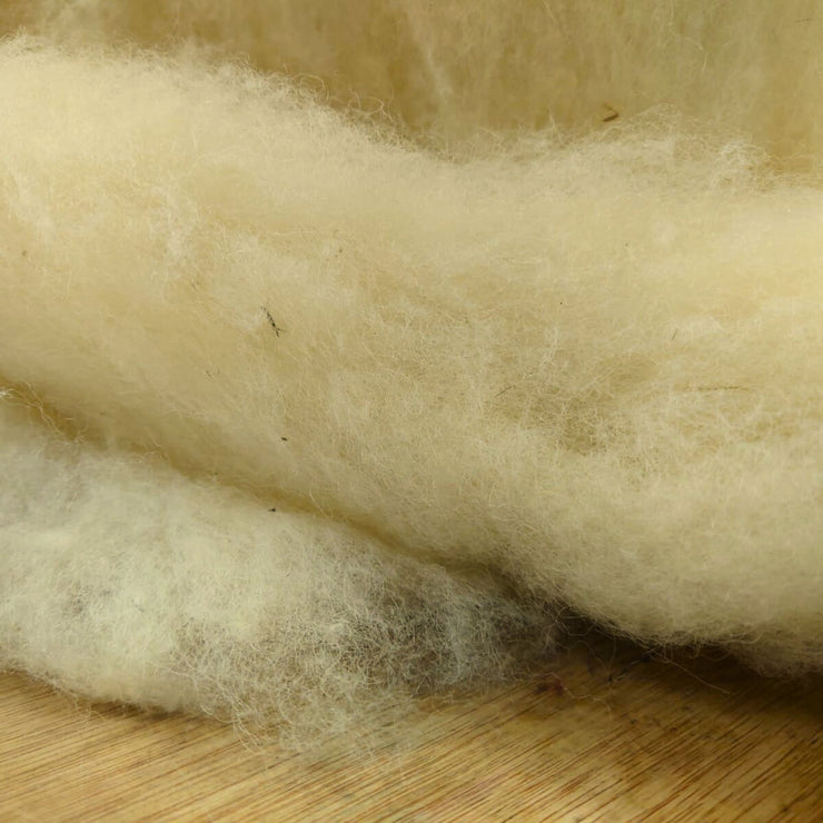 Close-up of raw wool fibers on a wooden surface