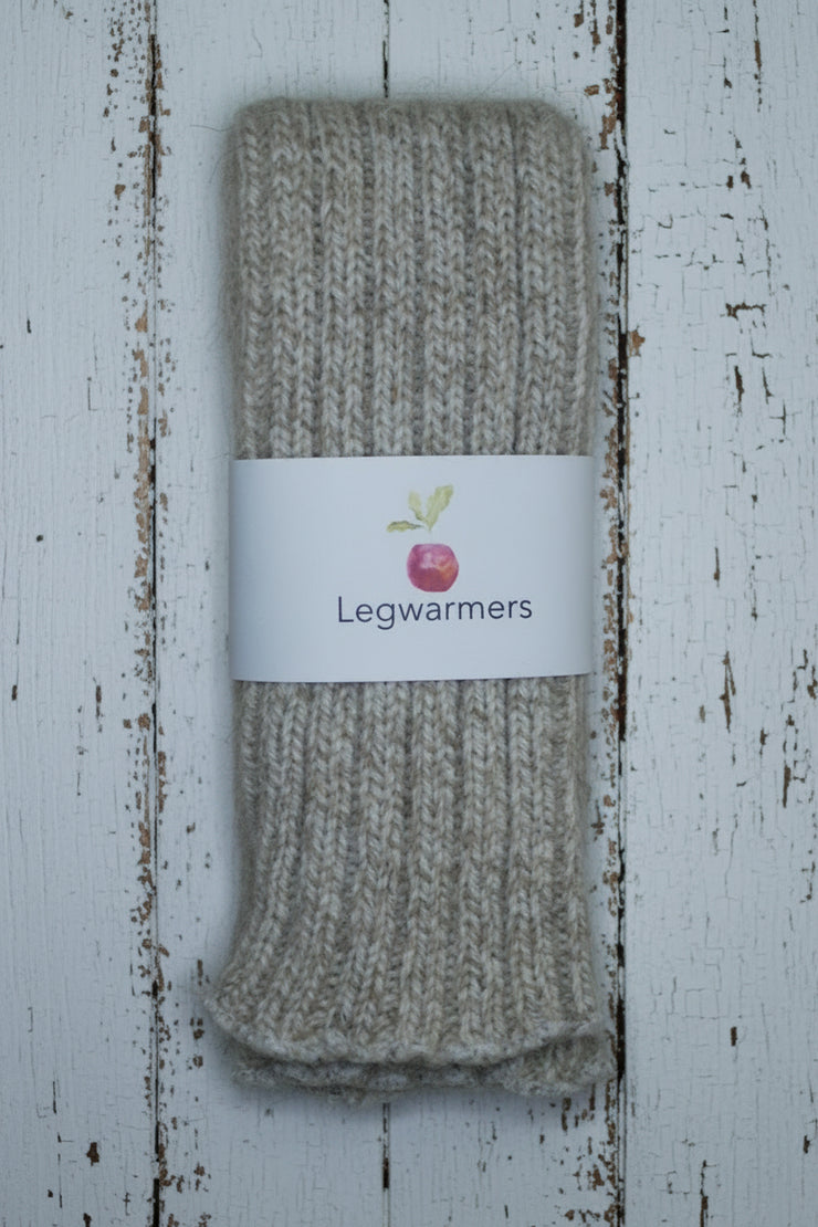 Pair of beige legwarmers with a label on a white wooden background