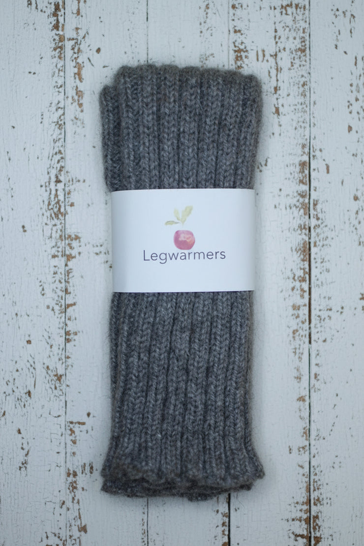 Pair of brown leg warmers with a brand label on a wooden surface