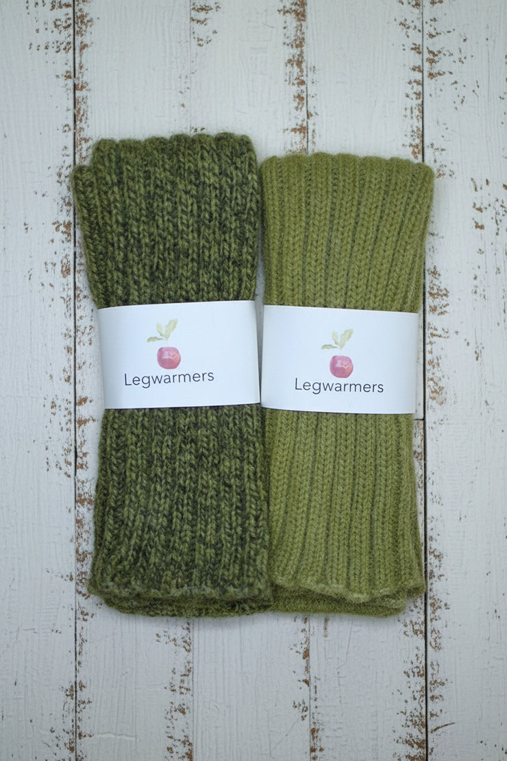 Pair of green legwarmers with a label on a wooden surface