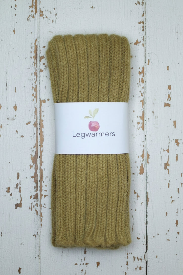Pair of mustard yellow legwarmers with a label on a wooden surface