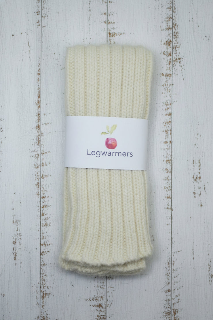 Pair of cream legwarmers with a label on a wooden surface