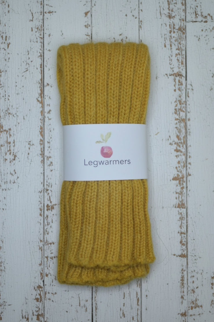 Mustard yellow legwarmers with a label on a wooden surface