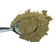 Pile of green weld extract powder with a spoon on a white background